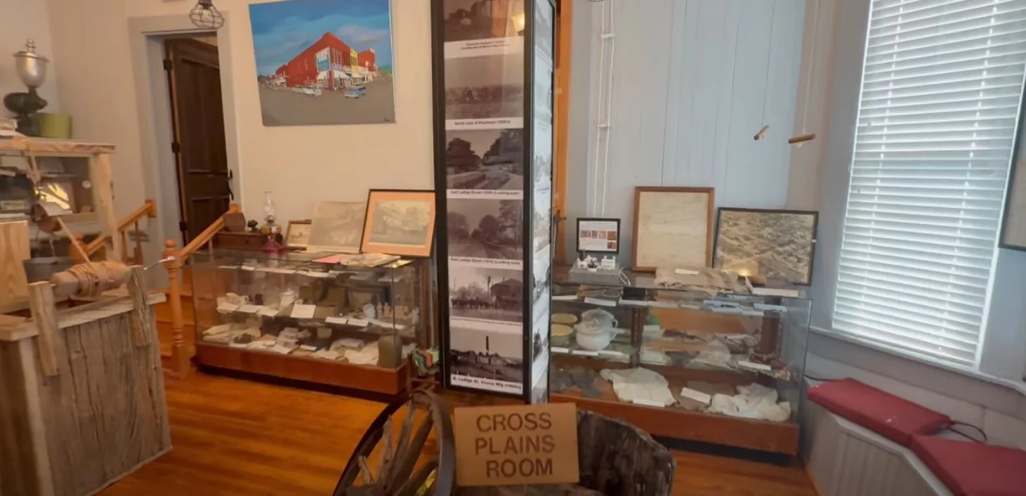 The Cross Plains Room — display cases of artifacts, historic photographs, and a painted mural of downtown Piedmont