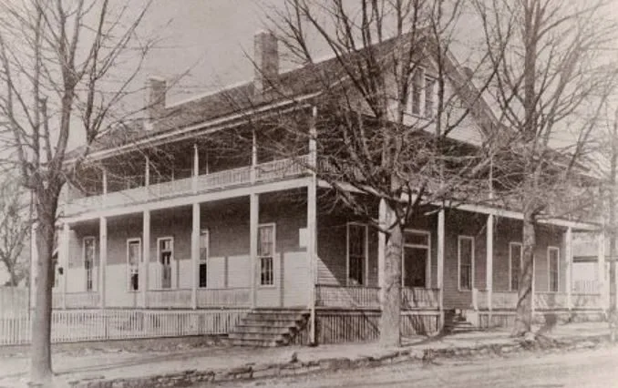 The wooden Albert House hotel with double porches behind bare winter trees