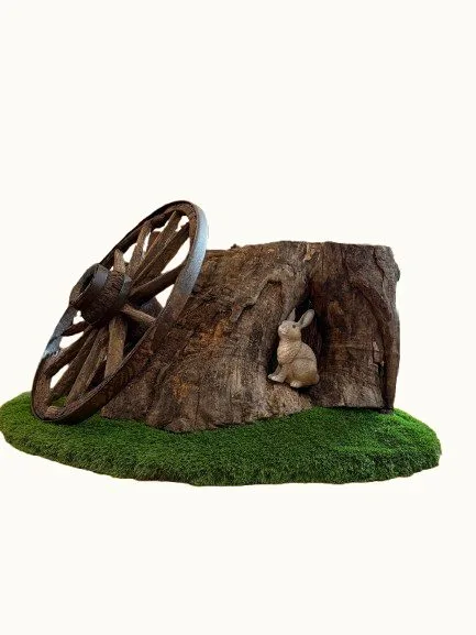 A life-sized replica of a hollow sycamore stump with a carved rabbit and a wagon wheel