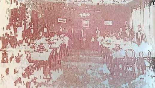 Waiters standing ready between set tables in a resort dining room