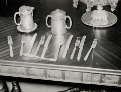 Silver forks and knives laid out on a polished table with serving pieces