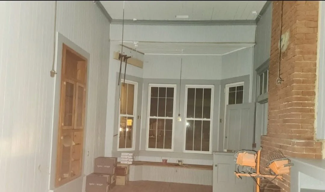 A depot room mid-restoration — bare walls, work lights, and boxes